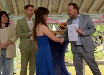 Schulleiter überreicht einer Absolventin der BG22 das Abschlusszeugnis mit Handschlag.